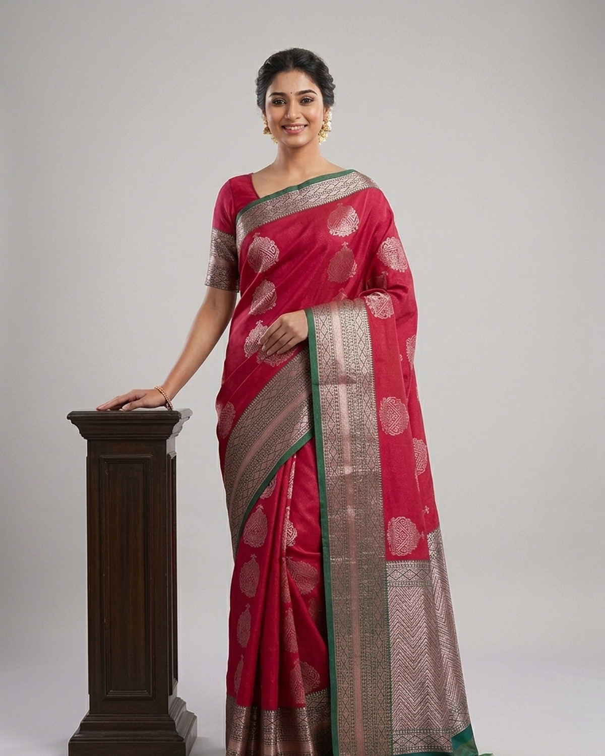 Model wearing a rose red cotton saree with bronze medallion motifs