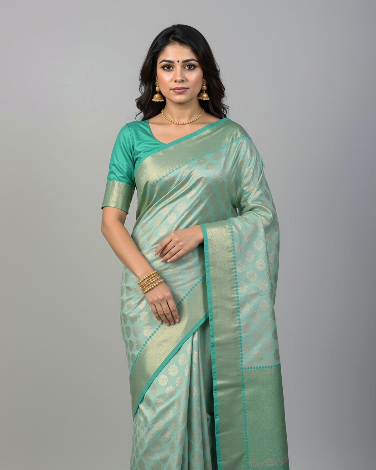Model wearing a sage green soft silk saree with a teal-edged gold border